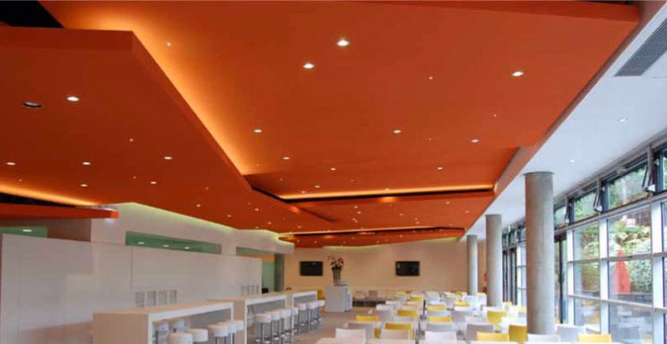 Interior de un restaurante con techos naranjas y mesas blancas. Iluminación suave.